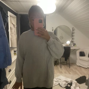 Grå sweatshirt - Säljer en mysig grå sweatshirt i normal passform.Tröjan har långa ärmar och ribbade muddar vid ärmslut och nederkant. Superbekväm och lätt att matcha med allt! Den är från NAKD i storlek XS, men väldigt oversize