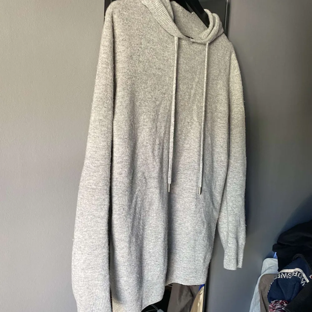 Säljer en supermysig grå stickad cashmere hoodie som är perfekt för kyliga dagar Den har en avslappnad passform med långa ärmar och en klassisk huva med dragsko Materialet är mjukt och bekvämt, vilket gör den idealisk för både vardag och hemmakvällar. Tröjor & Koftor.