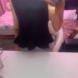 Svart spetsblus från KappAhl - Säljer en elegant svart spetsblus från KappAhl. Blusen har en volangdetalj vid nederkanten och är ärmlös.🖤