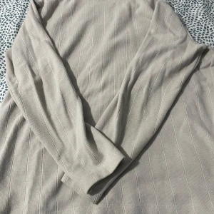 Beige ribbad tröja från Pull&Bear - Säljer en stilren beige ribbad tröja från Pull&Bear. Tröjan har långa ärmar och en mjuk känsla, perfekt för en avslappnad look. Passar bra till både jeans och kjol. Perfekt för höst och vår!