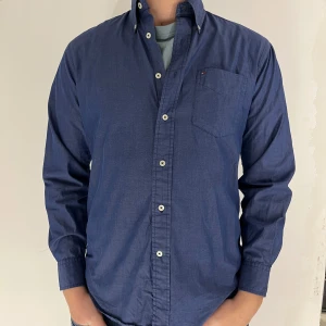 Blå Tommy Hilfiger skjorta - Snygg blå skjorta från Tommy Hilfiger med bröstficka. Skjortan är i storlek large och modellen är 193 och väger 85kg