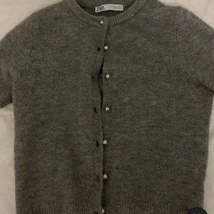 Grå kortärmad kofta från Zara💕 - Säljer denna gråa kofta från Zara eftersom att den är för liten för mig och inte kommer till användning🫶💕 koftan passar jätte bra hela året runt och stylas fint med ett vitt linne under🥰❤️ koftan har en liten direkt på en av knapparna men det går lätt att sy igen💕