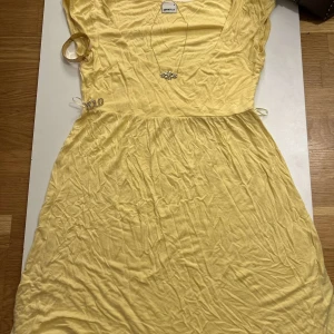 Gul klänning från Gina Tricot - Säljer en söt gul klänning från Gina Tricot. Klänningen har en v-ringad design och korta ärmar. Perfekt för sommarens varma dagar. 💛