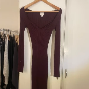 Vinröd ribbad klänning från H&M - Snygg vinröd ribbad klänning från H&M med lång ärm och v-ringad design. Perfekt för en stilren look. Klänningen är figurnära och har en elegant passform som framhäver silhuetten.