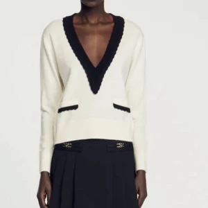 Vit och svart V-ringad tröja från Sandro - Snygg vit tröja från Sandro med svart V-ringning och svarta detaljer vid fickorna. Bra skick. Köpt för 2000 i Frankrike 