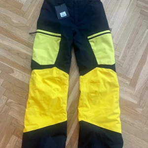  Gravity Pants Peak Performance - Snygga och funktionella skidbyxor från Peak Performance i svart och gul färg. Perfekta för utomhusaktiviteter med en cool design och bekväm passform. Strl 170 (motsvarande S) 
