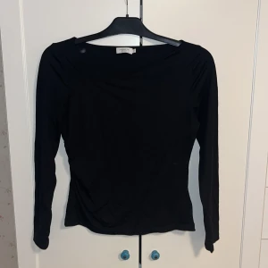 Svart långärmad topp från Stockh LM Studio - Snygg svart långärmad topp från Stockh LM Studio. Perfekt för en stilren look med sin enkla design och mjuka material. Passar bra till både jeans och kjol.