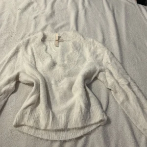 Vit fluffig tröja från Divided - Mysig vit tröja från Divided med fluffig textur. Tröjan har långa ärmar och en rundad nederkant. Perfekt för kyliga dagar när du vill ha något bekvämt och stilrent. 🧥✨