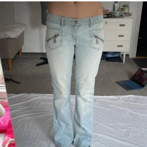 Ljusblå jeans - Snygga ljusblå bootcut jeans med coola dragkedjor på framsidan. De har en låg midja och fina bakfickor. Midjemått rakt över är 39-44cm (stretchiga) Lite slitna längst ned på byxorna. Hör av dig vid frågor💓