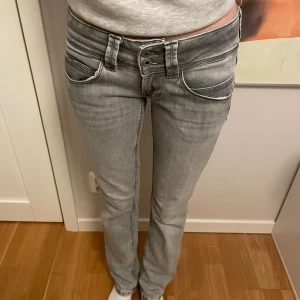 Grå jeans med låg midja - Snygga grå jeans med låg midja och dubbla knappar. De har en tight passform och klassisk femficksdesign. Perfekta för en avslappnad stil.
