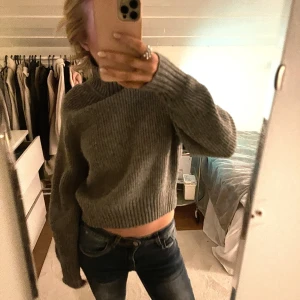 Grå stickad tröja - Säljer en mysig grå stickad tröja med långa ärmar och en croppad passform. Perfekt för kyligare dagar och lätt att matcha med jeans eller kjol. Hör av dig vid intresse!