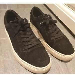 Svarta sneakers i mocka - Snygga svarta sneakers i mocka med vit sula och klassisk snörning. Perfekta för en stilren look och bekväma att bära hela dagen.