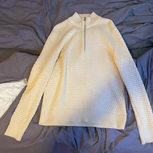 Beige stickad tröja från Selected Homme - Säljer en stilren beige stickad tröja från Selected Homme. Tröjan har en dragkedja vid halsen och är långärmad med ribbade muddar. Perfekt för kyligare dagar.