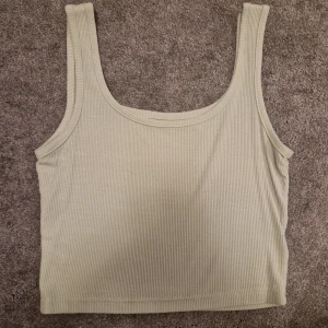 Grön ribbad linnetopp - Säljer en stilren grön ribbad linnetopp. Den har en enkel design som passar perfekt till både vardag och fest. Perfekt för varma sommardagar eller som ett lager under en jacka.