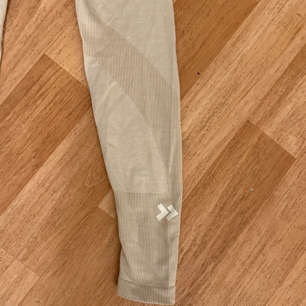 Snygga beige leggings med ribbade detaljer och hög midja. Perfekta för en bekväm och stilren look. De har en tight passform och är tillverkade i ett mjukt och stretchigt material.. Farkut & Housut.