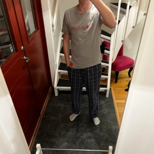 Grå t-shirt från Calvin Klein - Säljer en stilren grå t-shirt från Calvin Klein med röd logga på bröstet. T-shirten är kortärmad och har en liten röd etikett med CK-märke nedtill. Perfekt för en avslappnad look.