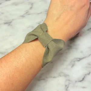 Grönt armband med rosett - Snyggt grönt armband med en elegant rosett-design av konstläder. Armbandet har en justerbar kedja i silverfärg för perfekt passform. Perfekt accessoar för att ge en stilren touch till din outfit.