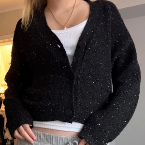 Stickad kofta - Säljer en svart kofta från MNG med glittriga detaljer. Koftan har långa ärmar och knappar framtill. Endast använd 2 gånger