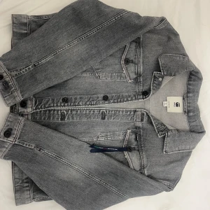 Grå jeansjacka från G-Star RAW - Snygg grå jeansjacka från G-Star RAW i klassisk design. Jackan har knappar framtill och två bröstfickor med lock. Perfekt för en stilren look.