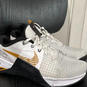 Sneakers Nike metcon 8 - Snygga Nike sneakers i vitt och svart med gulddetaljer. Skorna har en robust sula och snörning för bra passform. Perfekta för träning med Nike React-teknologi för extra komfort.