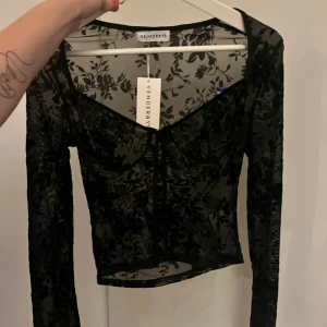 Svart blommig topp från Venderby's - Snygg svart blommig topp från Venderby's med långärmad design. Aldrig använd!