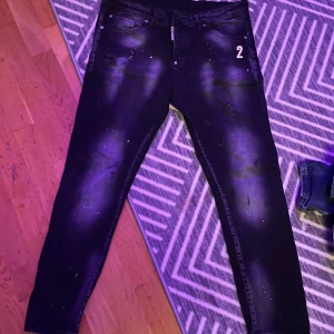 Svarta Dsquared 2 jeans - Snygga Dsquared 2 svarta jeans med ett coolt tryck av siffran '2' på framsidan. De har en dragkedja och klassisk femficksdesign. Perfekta för en stilren look. Passa på