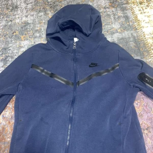 Navy blue tech fleece  - Säljer denna navy blue tech fleece då den är för liten för mig den ger ett bra intryck inte använd så jätte mycket men det finns en liten skada på den men de är sytt fint så inget man lägger märke till storlek 158-170 ny pris på den ligger runt 1000kr 