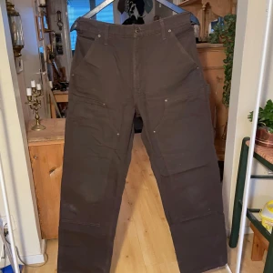 Bruna arbetsbyxor från Carhartt - Säljer ett par robusta bruna arbetsbyxor från Carhartt. De har en rak passform och är tillverkade i slitstarkt material.