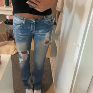 Ribbed bootcut jeans  - Snygga låg midja de blåa jeans med slitningar på låren och knäna. Det har fina detaljer med stenar vid knappar och gylfen. Midjemått: 79 cm innerbenslängd: 75 cm