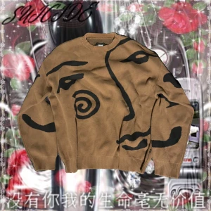 SWEET SKTBS TRÖJA - Säljer en unik beige tröja med ett konstnärligt ansiktsmönster i svart. Tröjan har långa ärmar och en rund halsringning. Perfekt för dig som vill sticka ut med en kreativ stil.