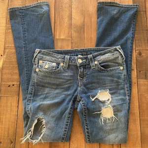 Blå jeans med slitningar från True Religion - Snygga blå jeans från True Religion med slitningar på framsidan. Bra skick. 450kr + frakt