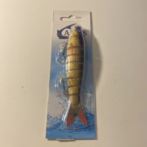 Fiskedrag från ARES - Säljer ett realistiskt fiskedrag från ARES, designat för att locka stora fiskar. Draget har en naturtrogen färgkombination av gul, svart och röd, med detaljerade mönster för att efterlikna en riktig fisk. Perfekt för sportfiskeentusiaster som vill ha ett effektivt bete i sin samling.