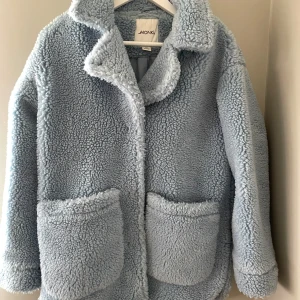 Ljusblå teddyjacka från Monki - Mysig trendig ljusblå teddyjacka från Monki med stora fickor framtill.