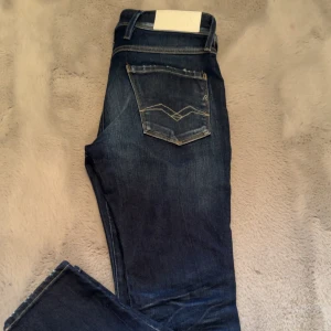 Mörkblå jeans från Replay - Snygga mörkblå jeans från Replay med klassisk femficksdesign och diskreta slitningar. Jeansen har en knappgylf och är perfekta för en avslappnad stil. De har en normal passform. Storlek:29-32