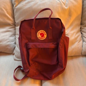Fjällräven kånken  - Fjällräven Kånken – Nästintill oanvänd!  Säljer en nästintill oanvänd Fjällräven Kånken i Röd, som bara har använts ett fåtal gånger vid photo shoots . Väskan är i nyskick, mest samlat damm.   Perfekt för både vardag och friluftsliv – lätt, slitstark och bekväm att bära.  Detaljer: -Original Fjällräven Kånken -Rymmer 16L -Klassisk design med sittunderlag i ryggfickan -Justerbara remmar  Nypris: 1299kr på Fjällrävens egna hemsida.