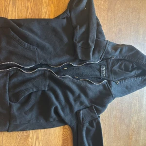 Svart hoodie från Primark - Säljer en svart hoodie från Primark med dragkedja och huva. Den har långa ärmar och praktiska fickor framtill. Perfekt för en avslappnad stil eller en lätt kofta över linnet/tshirt 