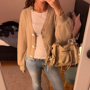 Beige kofta - Säljer en mysig beige ribbad kofta med stora vita knappar. Koftan har långa ärmar och en avslappnad passform😽 