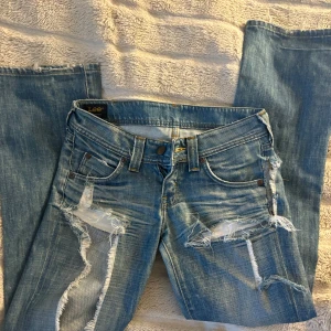 Blå jeans från Lee med slitningar - Snygga lågmidjade jeans från Lee. Ganska många & stora slitningar, samt ett hål vid höften därav priset!  Men inget som inte enkelt går att fixa. Personligen älskar jag det, säljer pga att de är alldeles för små💕💕