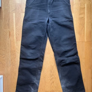 Svarta arbetsbyxor från Carhartt - Säljer ett par svarta arbetsbyxor från Carhartt. Byxorna har flera praktiska fickor och en robust design. Perfekta för arbete eller fritid där slitstyrka behövs. Size 33x34