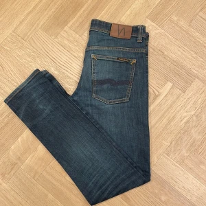 Mörkblå jeans från Nudie Jeans - Snygga mörkblå jeans från Nudie Jeans med klassisk femficksdesign. Jeansen är i mycket bra skick. Modellen på bilden är 185cm lång. Hör gärna av er i dm om exakta mått, fler bilder eller funderingar🤗