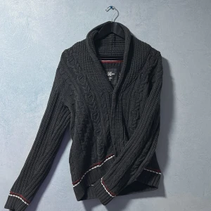 Stickat cardigan H&M - Säljer en riktigt snygg och skön stickad cardigan tröja från H&M i grå färg med vita svarta och röda detaljer. Säljer tröjan pga den är lite liten för mig. Tröjan har väldigt snygga stickade detaljer vilket lyfter hela plagget, de röd och svarta och vita detaljerna är verkligen pricken över i:et och gör tröjan väldigt snygg. Tröjan är i väldigt bra skick och är i Storlek M och som sagt från H&M. Skick 9/10, storlek Medium