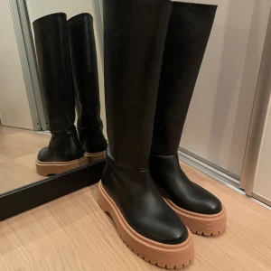 Svarta stövlar med tjock sula - Snygga svarta stövlar i skinn med en robust brun sula. Perfekta för alla säsonger med en stilren design som passar till många outfits. Använda ett fåtal ggr! 