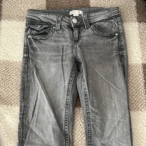 Grå jeans från Gina Tricot - Snygga grå jeans från Gina Tricot i storlek 146 , Low rise. De har en klassisk femficksdesign med knappar och dragkedja framtill. Perfekta för en avslappnad stil. 