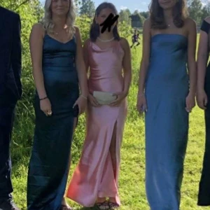 Rosa klänning till bal  - Elegant rosa långklänning i satin med en stilren slits på sidan. Klänningen formar sig efter kroppen! Den är uppsydd till mig som är ca 160 cm, så passar på korta människor. Det är storlek S men skulle säga att den sitter mer som en XS. Perfekt till bal eller bröllop