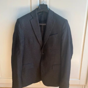 Svart kavaj - Snygg svart kavaj med klassisk design och enkel knäppning. Perfekt för både formella och semi-formella tillfällen. Kavajen har en stilren passform och är tillverkad i ett material som ger en elegant look. Pris kan diskuteras.