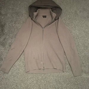 Massismo dutti cardigan - Killen på bilden är 185 cm och 68 kg. Säljer en beige ribbad hoodie med dragkedja. Tröjan har en huva och långa ärmar, perfekt för kyligare dagar. Den är stilren och enkel att matcha med olika outfits. Riktigt skön