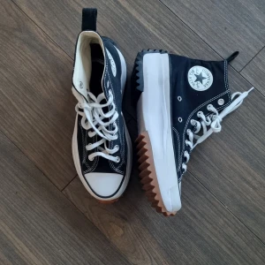 Svarta Converse All Star sneakers - Snygga svarta Converse All Star sneakers med vit sula och klassisk snörning. Skorna har en hög modell med den ikoniska stjärnloggan på sidan och en robust sula för extra komfort. Säljer de pga jag aldrig använder de, har haft de I några år nu men har använt de typ 3 gånger så de ser fortfarande nästan nya ut :)