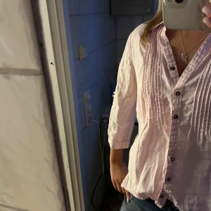 Ljusrosa blus med knappar - Säljer en ljusrosa blus med knappar framtill och trekvartsärmar. Super fin som knappt är använd💕