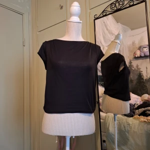 Svart topp från HM - Säljer en stilren svart topp från HM. Toppen har en enkel design med korta ärmar och rak hals. Perfekt för en minimalistisk look.