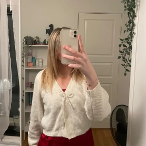 Vit ribbad kofta med pärldetalj - Säljer en söt vit ribbad kofta med en fin pärldetalj framtill. Koftan är croppad och har långa ärmar, perfekt för en stilren look. Passar bra till både kjol och byxor. Hör av dig vid intresse! 🤍